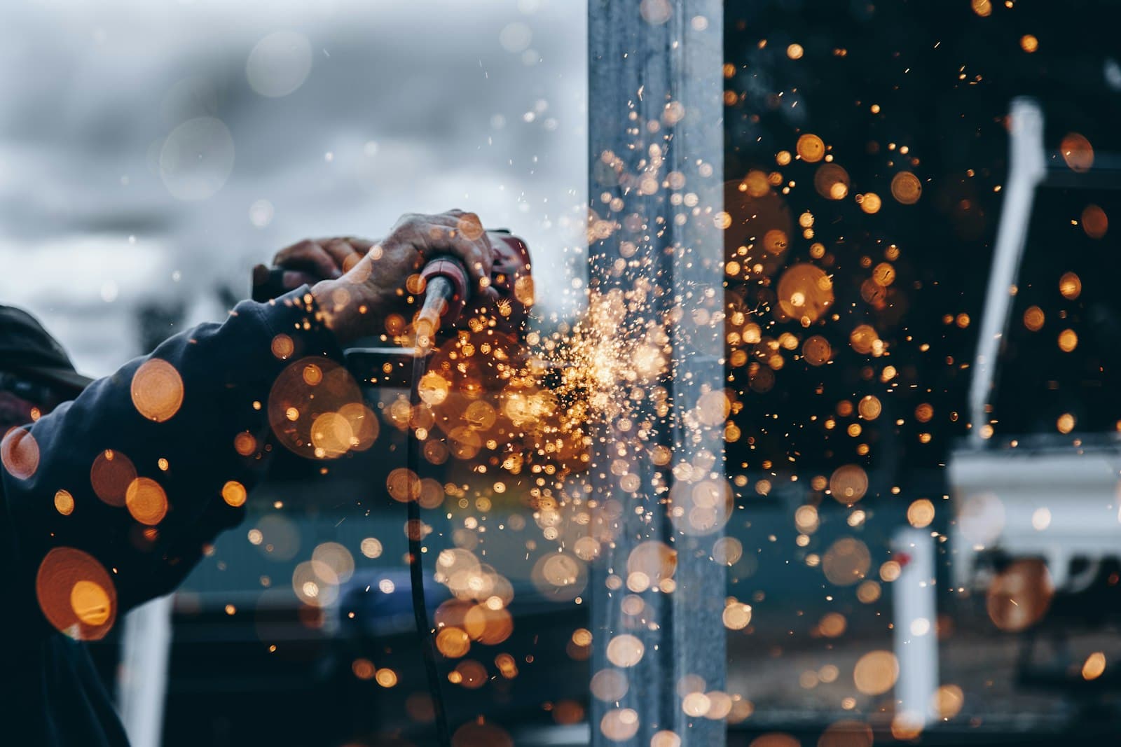 Engineer grinding a press component in the workshop, sparks flying